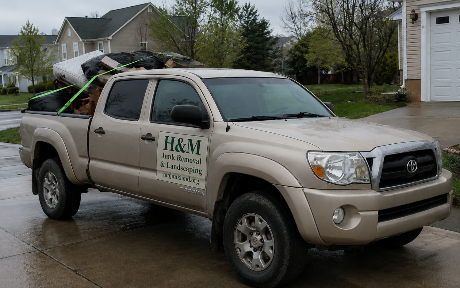 H&M truck loaded with a junk haul in a driveway